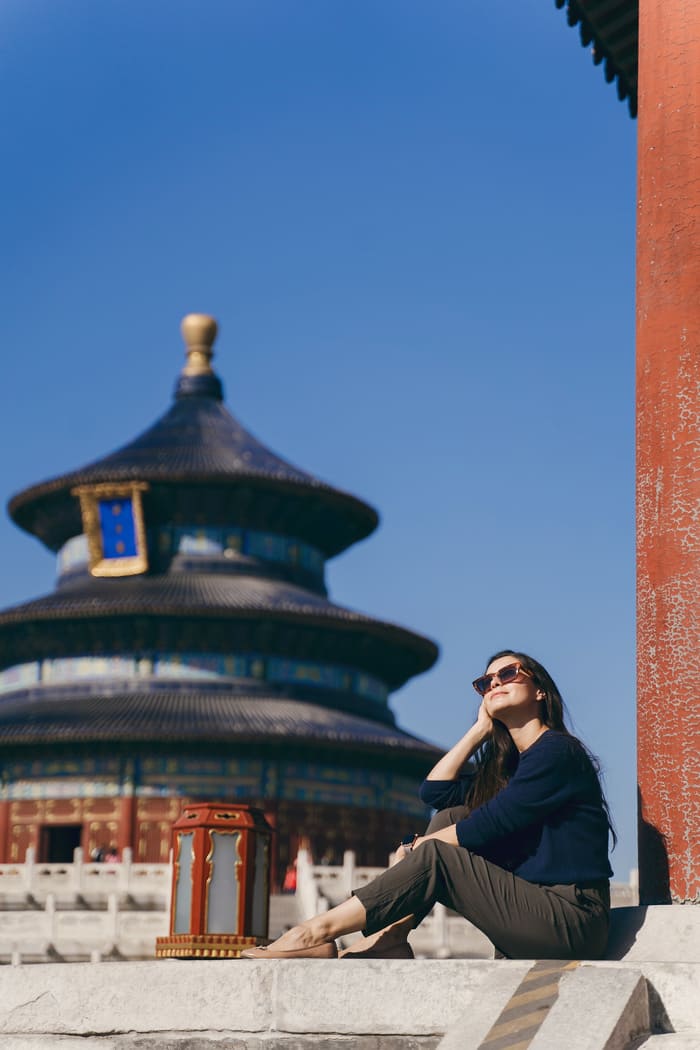 mujer sentada y atras un monumento en beijing